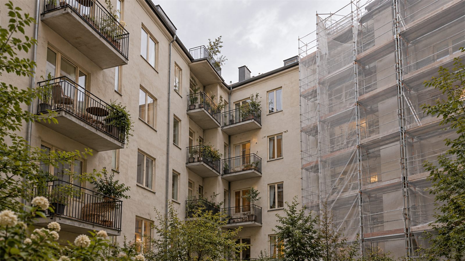 Innergård i ett flerbostadshus med balkonger och en byggnadsställning längs ena fasaden.